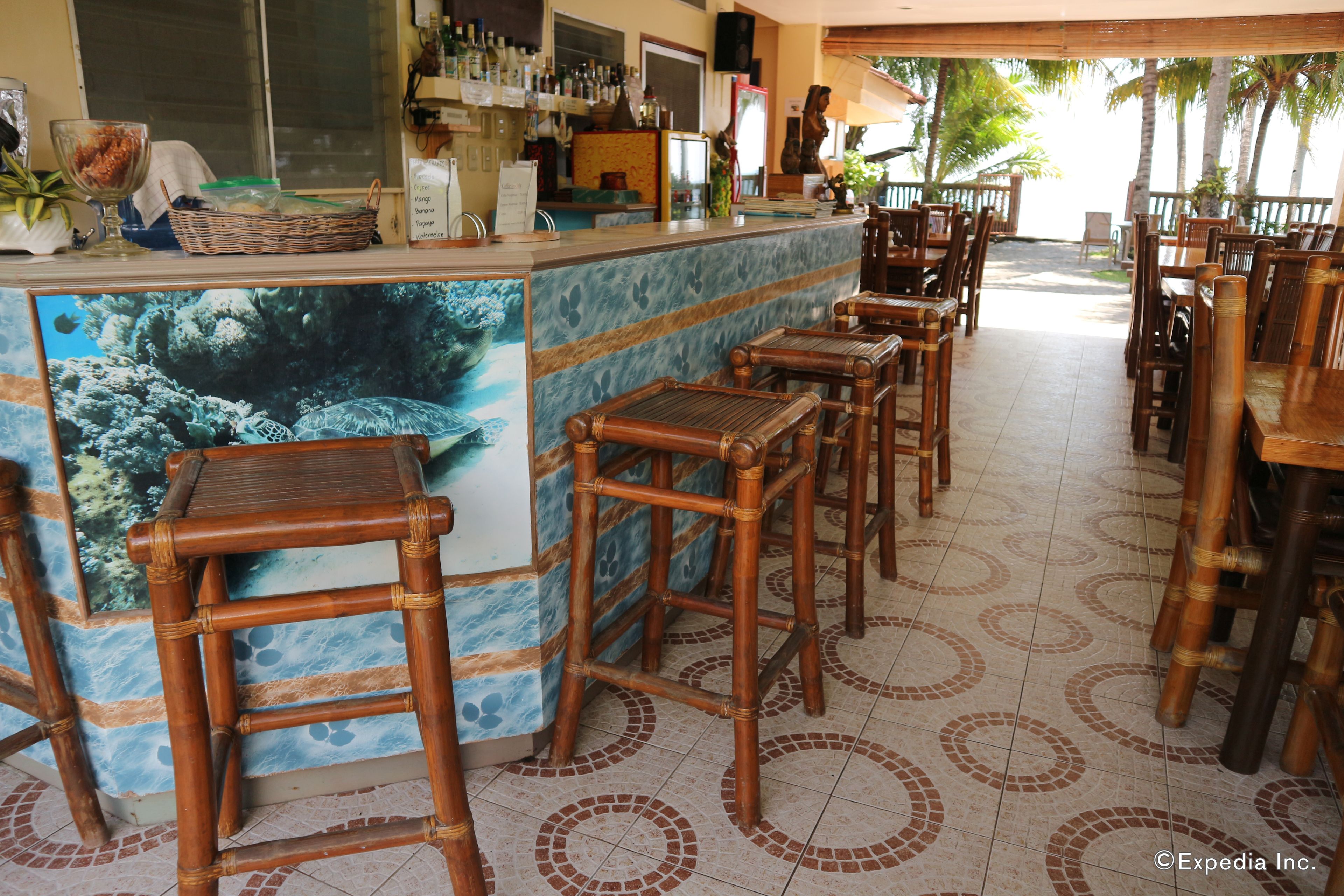 A restaurant with a bar area, bamboo chairs, and a tiled floor with circular patterns.