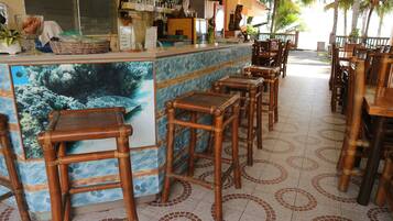 A restaurant with a bar area, bamboo chairs, and a tiled floor with circular patterns.
