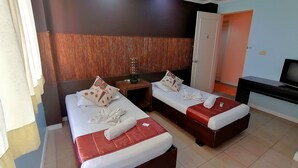 Habitación de hotel con dos camas, un televisor, una mesita y una puerta.