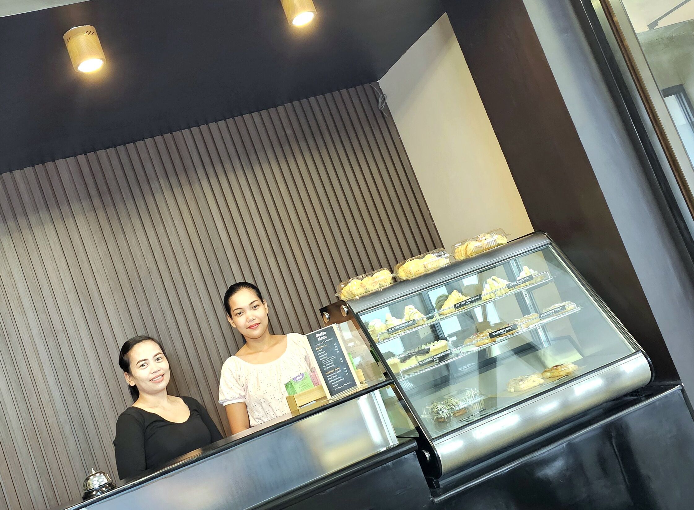 A bakery display with various pastries in a modern interior with vertical wooden slats on the wall.