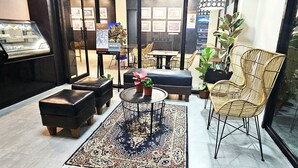 Un interior moderno con una zona de estar que incluye una mesa redonda, dos otomanas negras y una silla de mimbre.