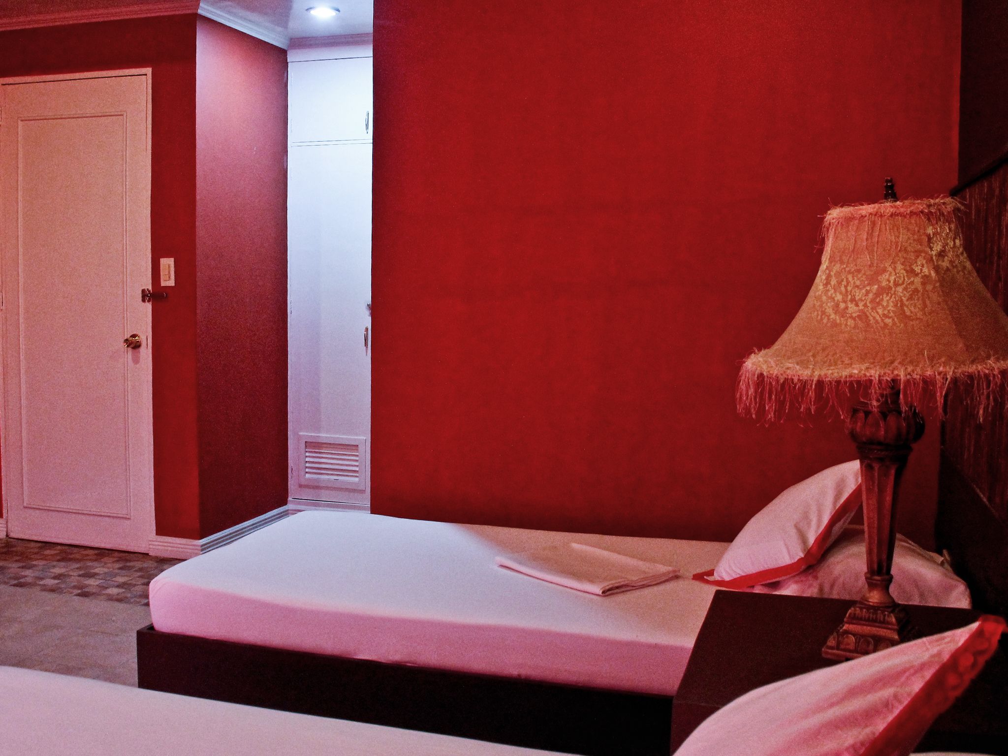 A hotel room with a bed, a lamp, and a door.