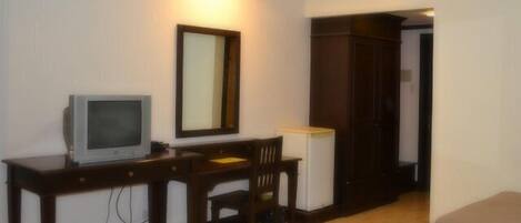 A room with a wooden desk, a television, a chair, and a wardrobe.