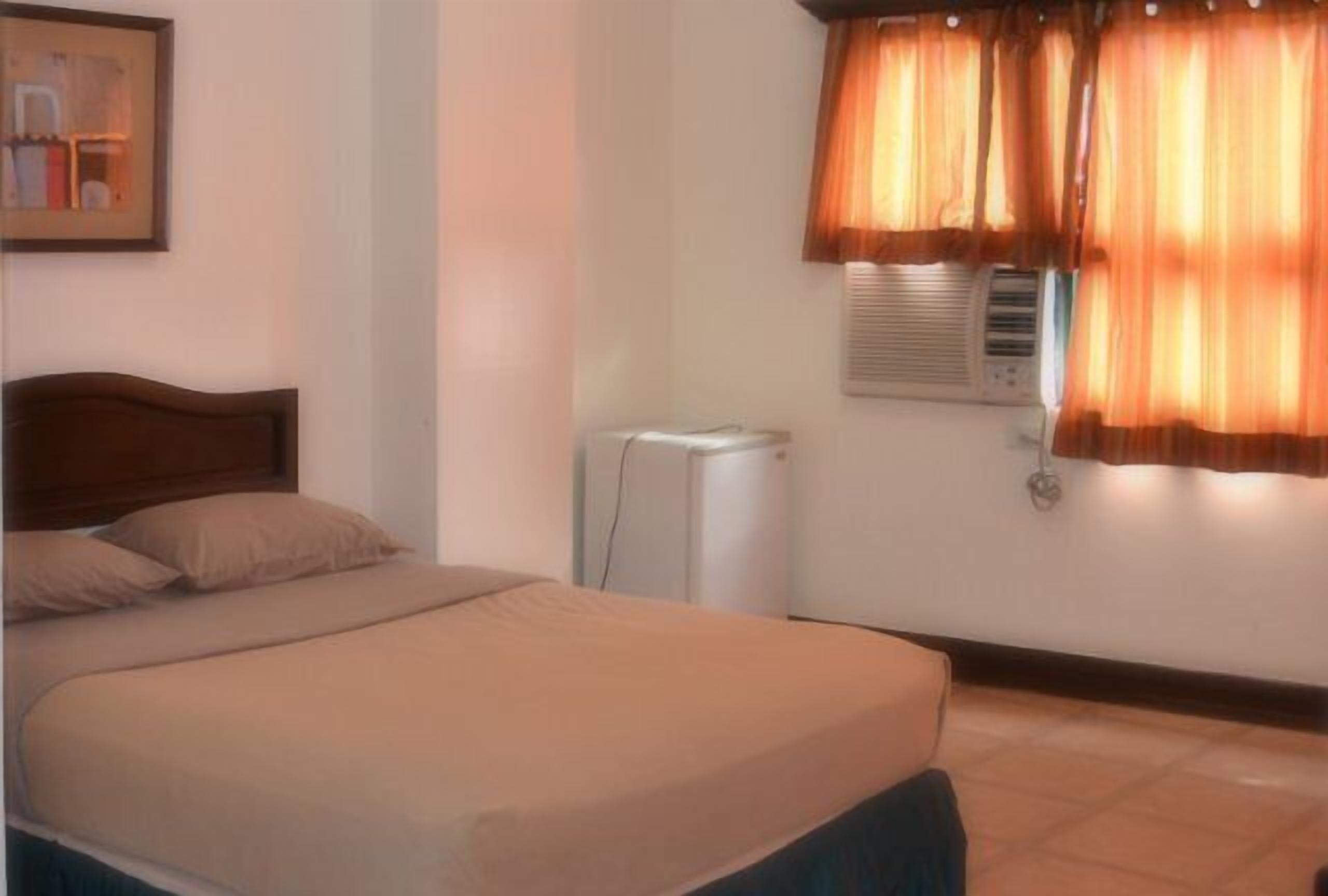 A bedroom with a bed, a heater, and a window with curtains.