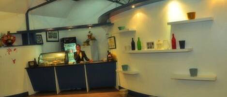 A kitchen area with a counter, shelves with bottles, and a ceiling with exposed beams.