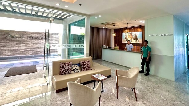 A modern hotel lobby with a reception desk, a sofa, and chairs. - Ace Penzionne (Lapu-Lapu)