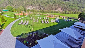 Um resort com gramado bem cuidado, espreguiçadeiras e vista para uma montanha arborizada.