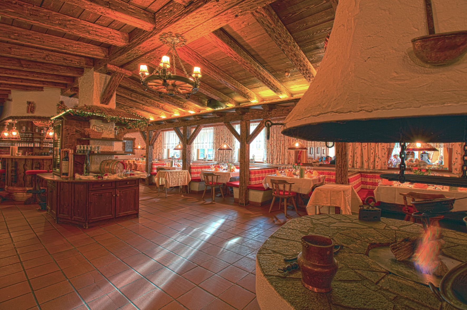 Een rustiek interieur met houten balken, een centraal gelegen open haard en een bar.