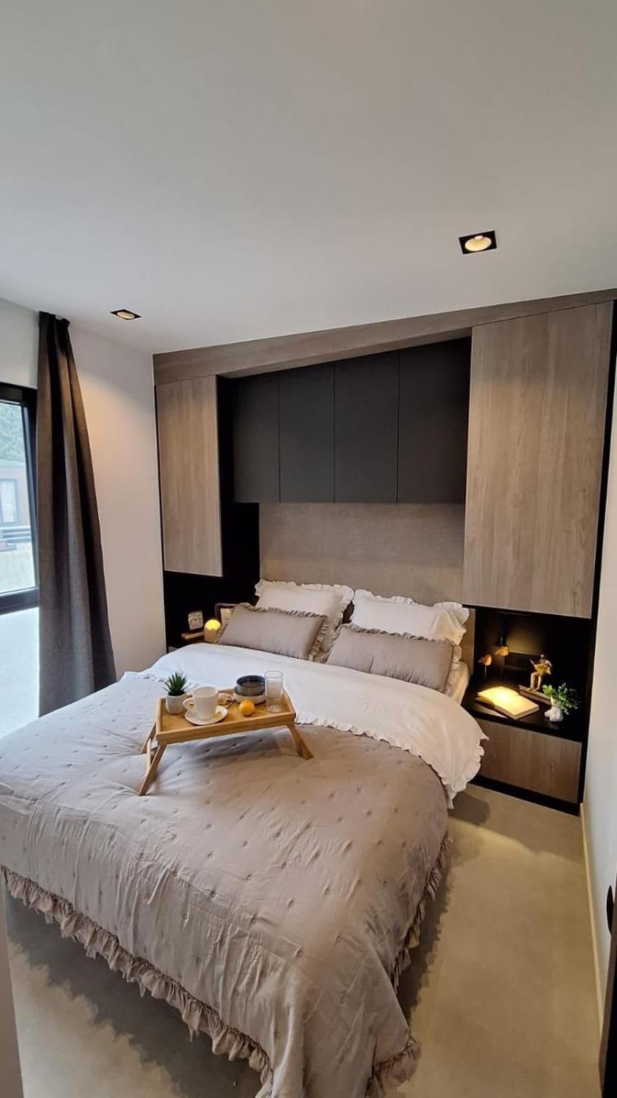 Un dormitorio moderno con una cama grande, mesitas de noche y televisión integrada.