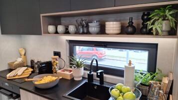 A modern kitchen with a black countertop, a sink, and a window with a view of a red car outside.