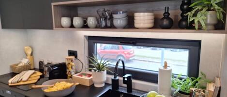 A modern kitchen with a black countertop, a sink, and a window with a view of a red car outside.
