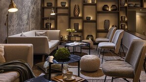 Un salon moderne comprenant un canapé, des fauteuils, une table basse et une bibliothèque remplie d’objets décoratifs.
