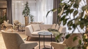 Un salon moderne avec un canapé, des fauteuils, une table basse et une plante en pot.