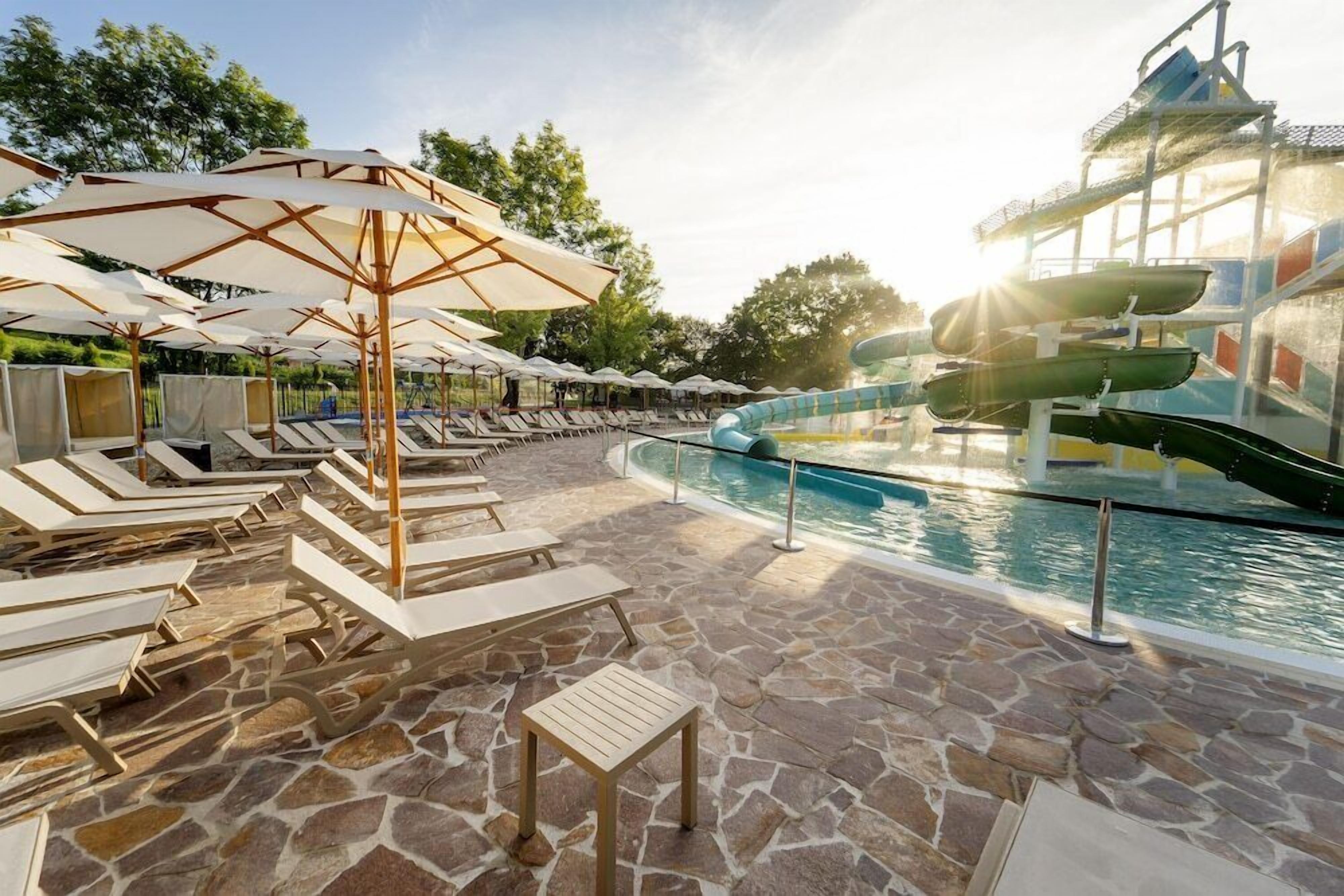 A poolside area with lounge chairs, umbrellas, and a water slide.