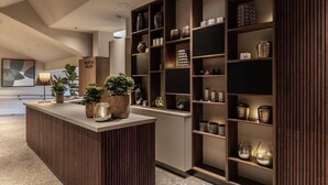Un espace d’accueil avec un comptoir en bois, des plantes en pot et des étagères ornées d’objets décoratifs.