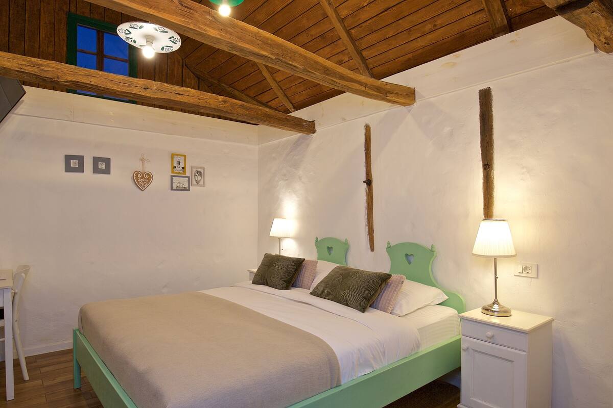 A bedroom with a bed, bedside table, lamp, and wall decorations.
