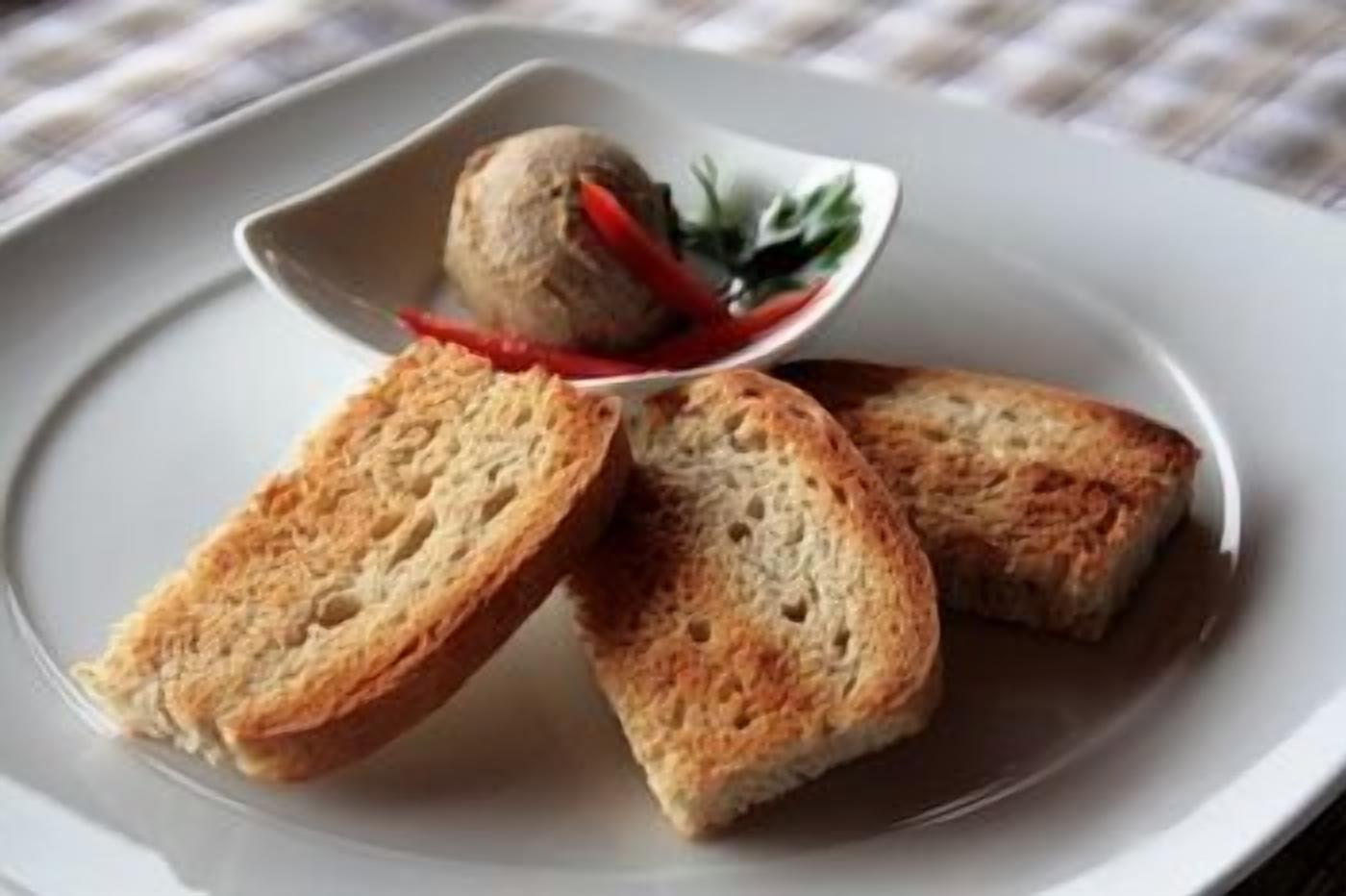 A plate with two slices of toasted bread and a small bowl of a food item.
