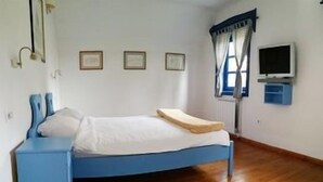 A bedroom with a bed, a nightstand, a television, and framed pictures on the wall. - Vuglec Breg (Krapina)