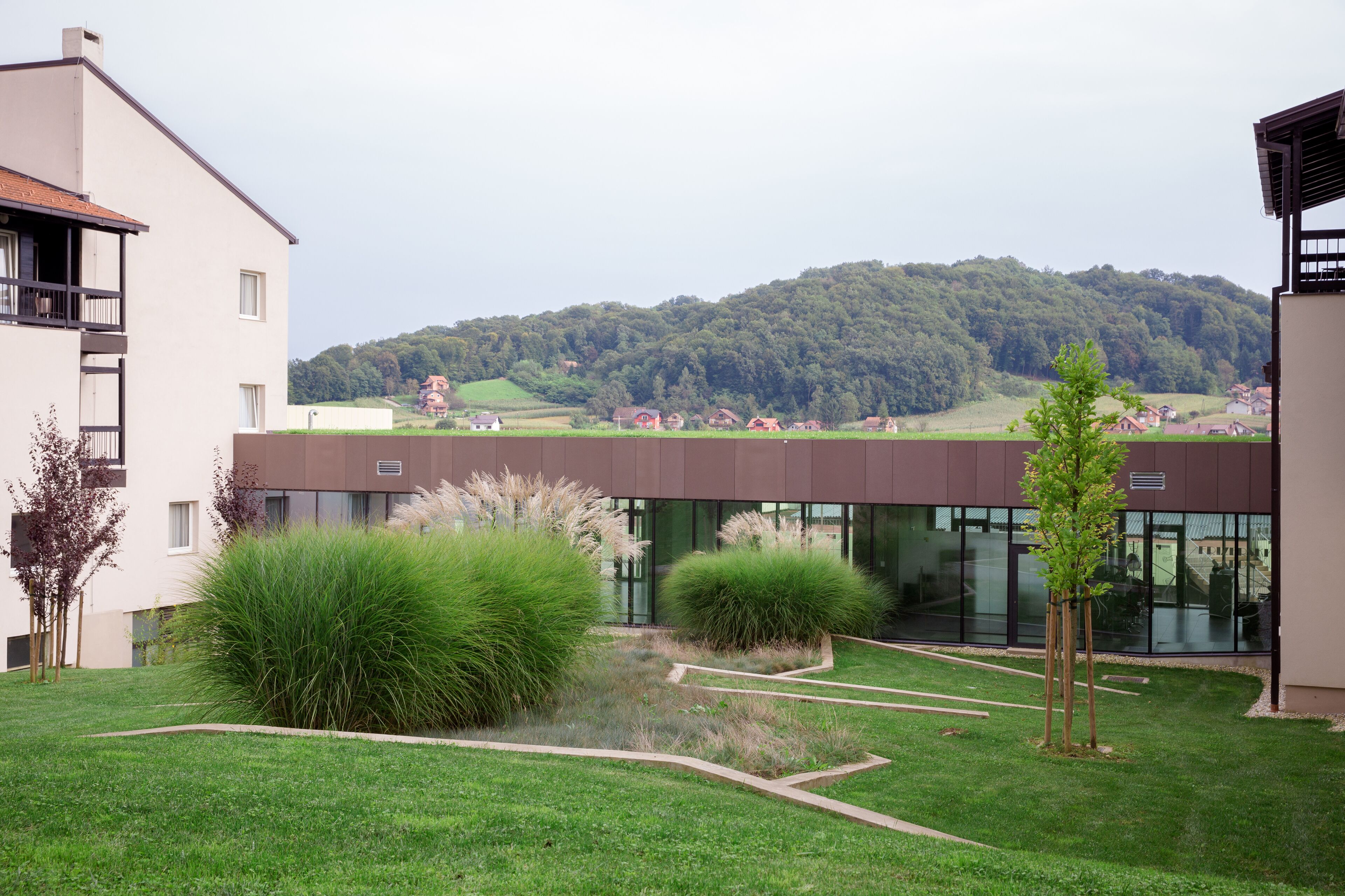 A modern building with a glass facade, surrounded by well-maintained grass and shrubs.