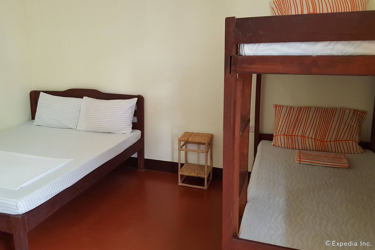 A room with a single bed, a small wooden stool, and a bunk bed.
