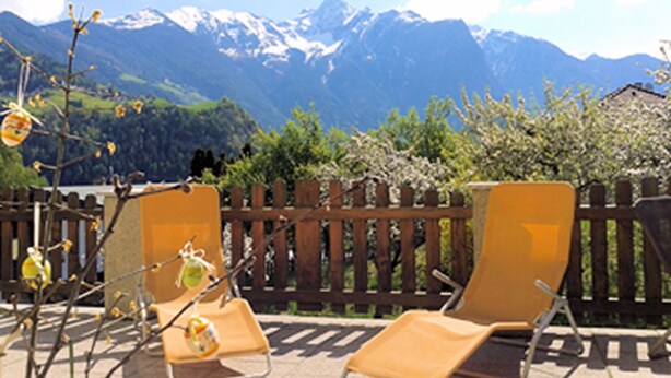 A patio with two lounge chairs and a wooden fence, overlooking a mountainous landscape. - Gästehaus Hackl (Sautens)