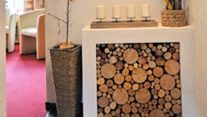 A cozy room with a fireplace, a wall-mounted shelf with candles, and a decorative heart hanging above it. - Gästehaus Hackl (Sautens)