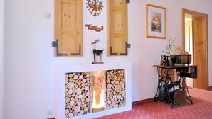 A room with a fireplace, wooden cabinets, and a sewing machine. - Gästehaus Hackl (Sautens)