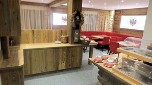 A restaurant with wooden walls and a counter, red seating, and a buffet area. - Gästehaus Hackl (Sautens)