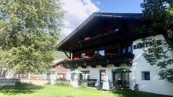 Un edificio de estilo chalé tradicional con techo inclinado, balcones de madera y jardineras con flores.