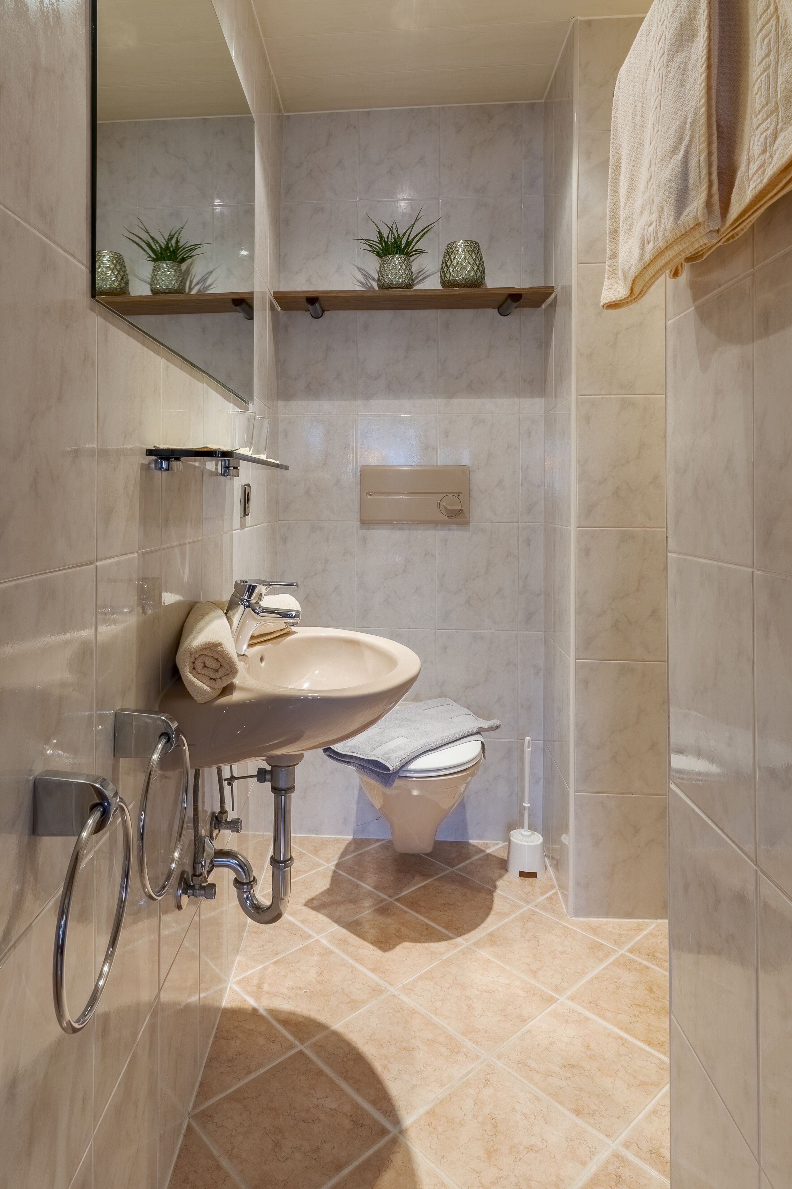 A bathroom with a sink, mirror, towel rack, toilet, and shower.