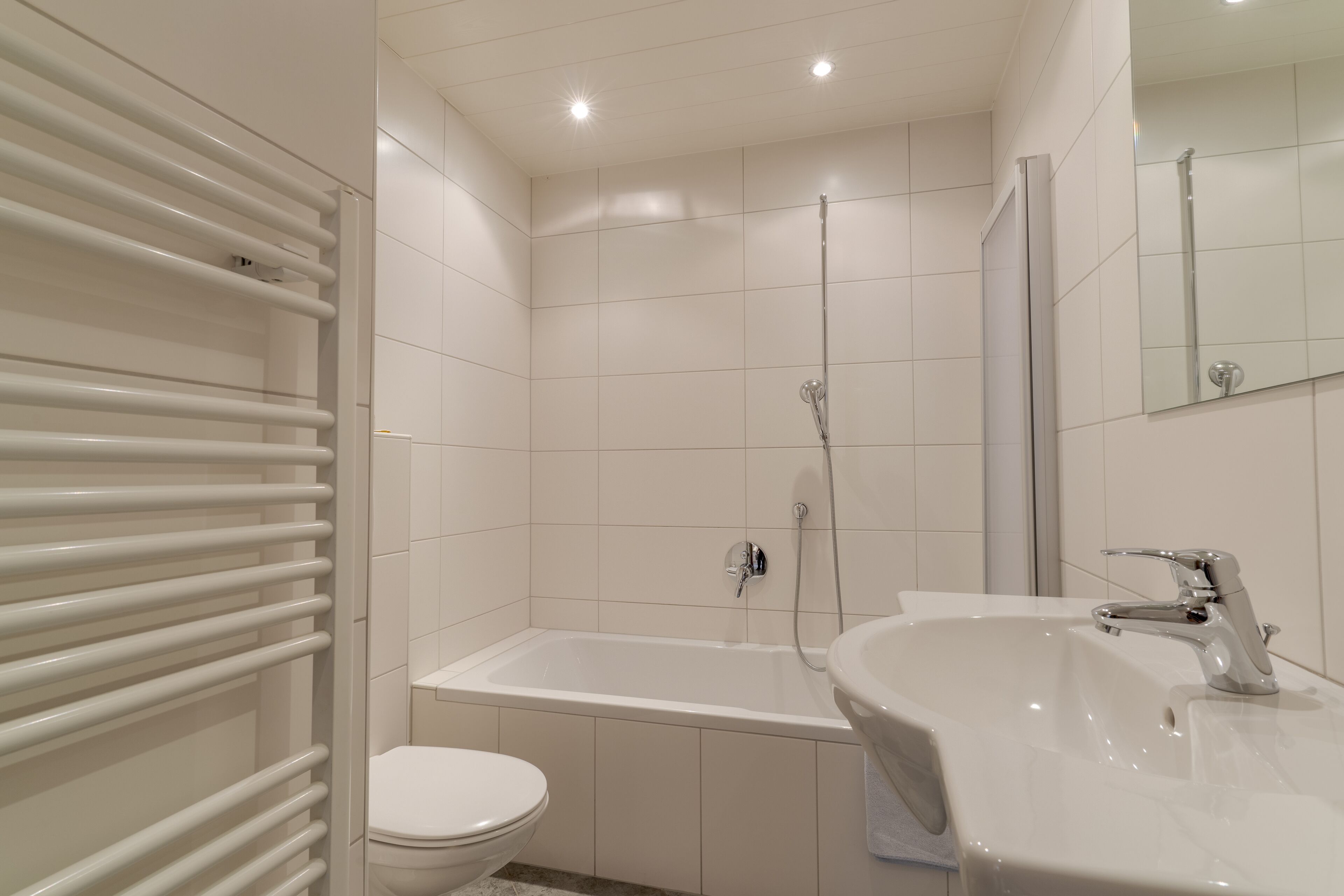 A modern bathroom with a bathtub, toilet, and sink.