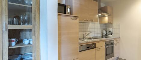A modern kitchen with wooden cabinets, a stainless steel oven, and a dishwasher.