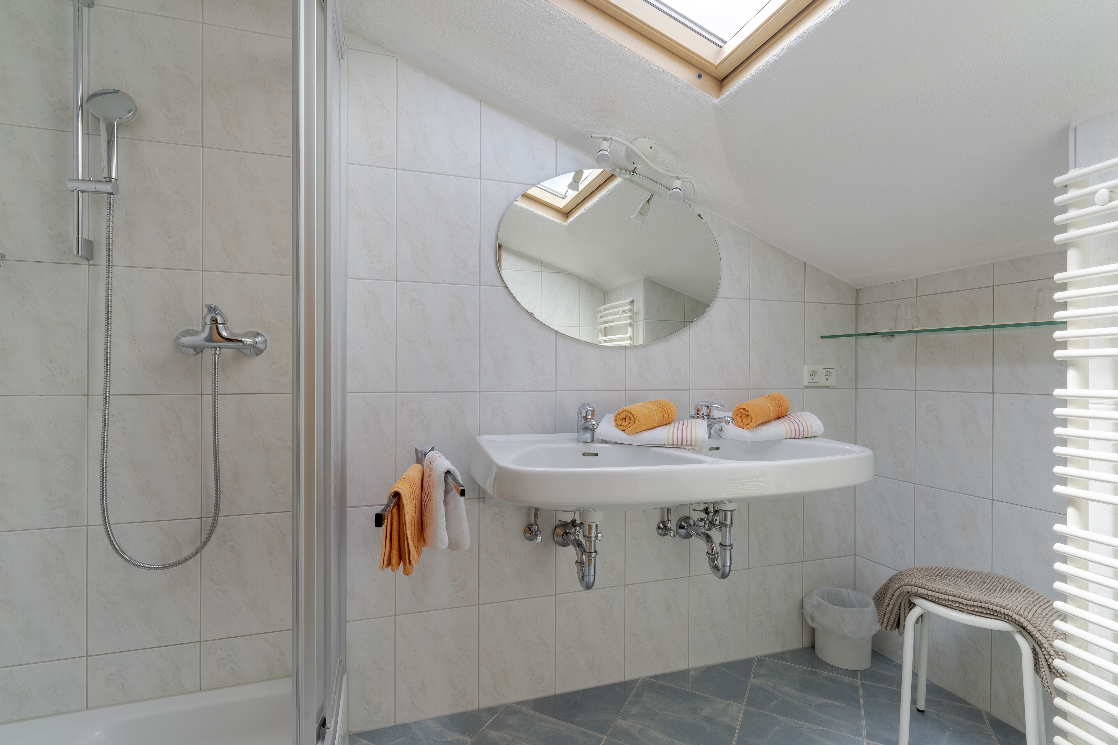 A modern bathroom with a shower, a sink, a mirror, and a glass shelf.