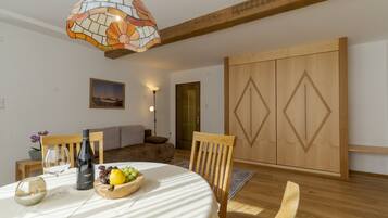 A dining area with a round table, chairs, a wine bottle, and a fruit bowl.