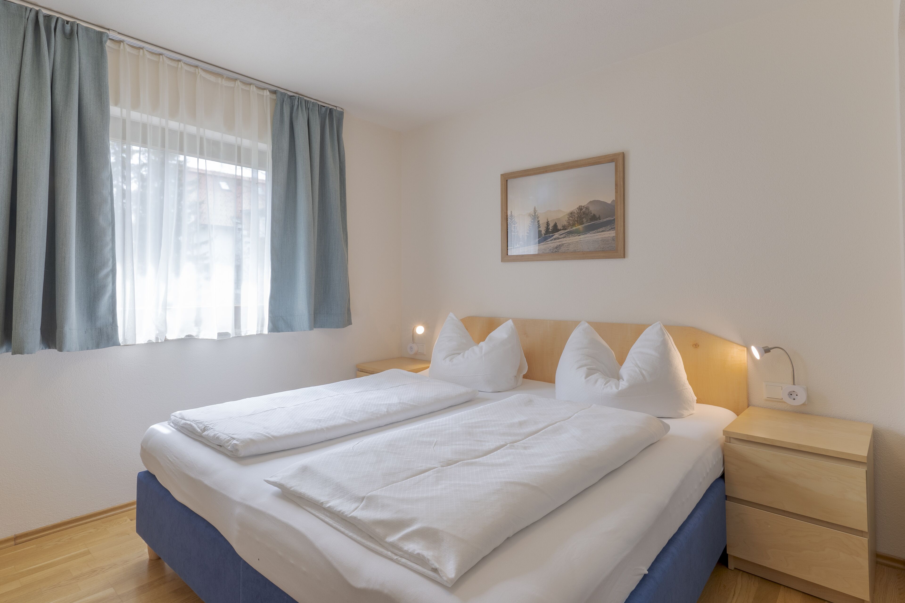 Un lit bien fait, avec du linge de lit blanc, une tête de lit en bois et une table de chevet avec une lampe.