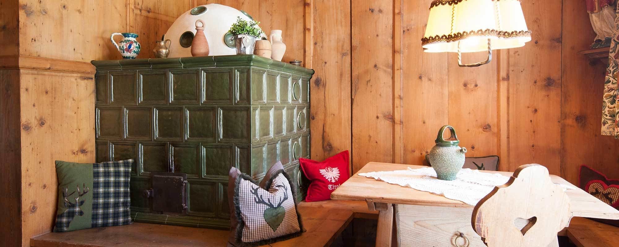 A wooden cabin interior with a green cabinet, a wooden table, and a bench.