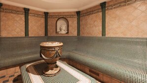 A room with a mosaic-tiled bench, a decorative urn, and a bust in the background. - Hotel Piz Buin (Ischgl)