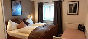 Un dormitorio con cama doble, una ventana con cortinas y un cuadro enmarcado en la pared.