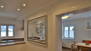 A modern kitchen with a large mirror, wooden countertop, and built-in shelves. - Haus Montana (Lermoos)