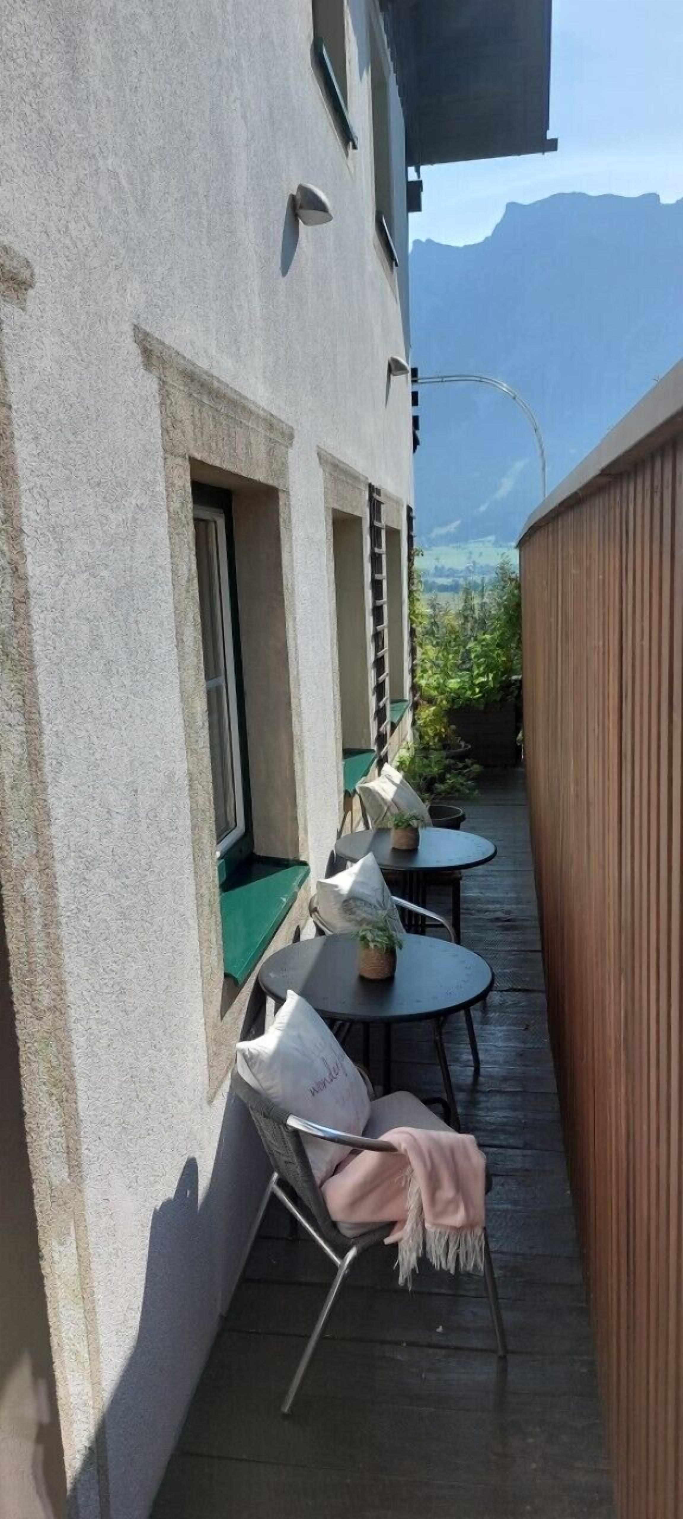 A terrace with outdoor seating, a wooden fence, and a mountain view.
