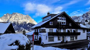 A two-story building with a snow-covered roof, large windows, and a balcony. - Haus Montana (Lermoos)