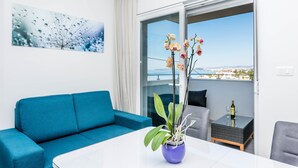 A modern living room with a blue sofa, a white table, and a potted orchid. - Villa Lavanda (Podstrana)