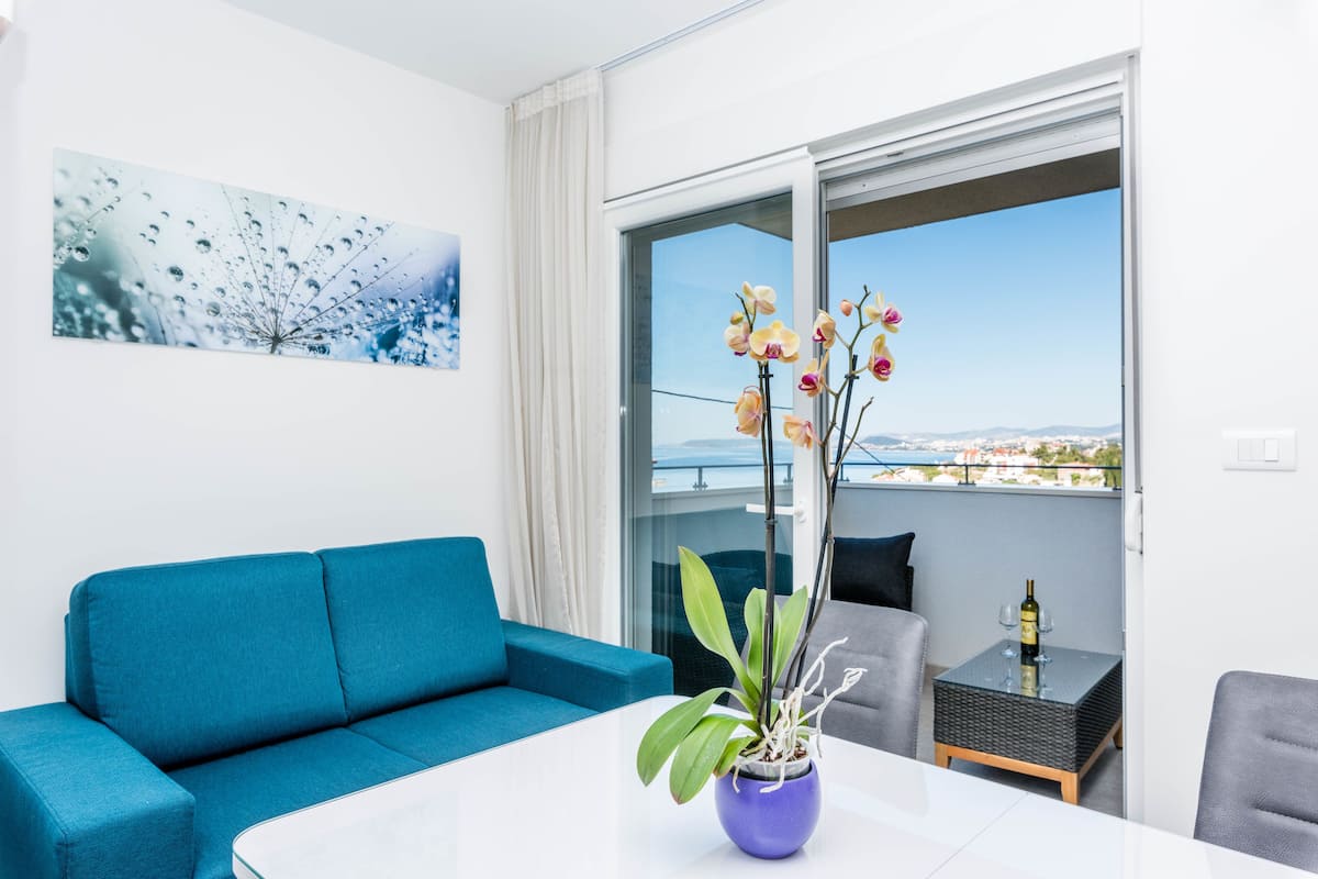 Un salon moderne avec un canapé bleu, une table blanche et une orchidée en pot.