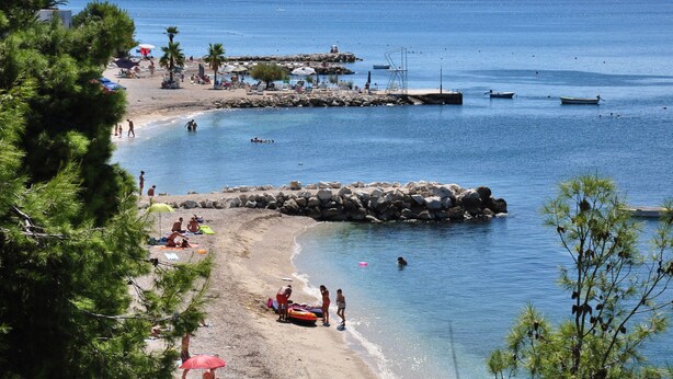 A beach with clear blue water, rocky formations, and a few boats. - Villa Lavanda (Podstrana)