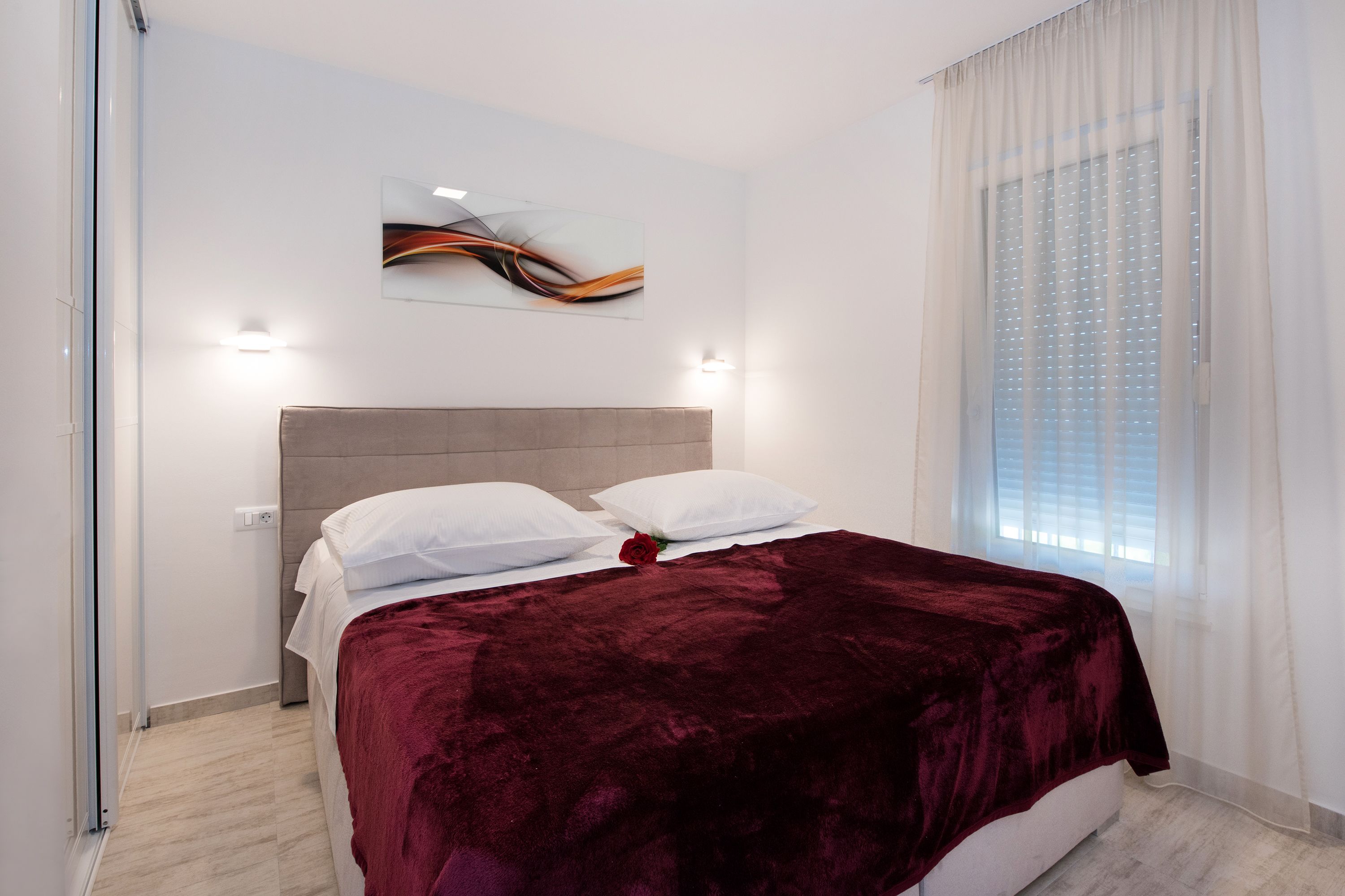 Een moderne slaapkamer met een groot bed, een hoofdbord en een wanddecoratie.
