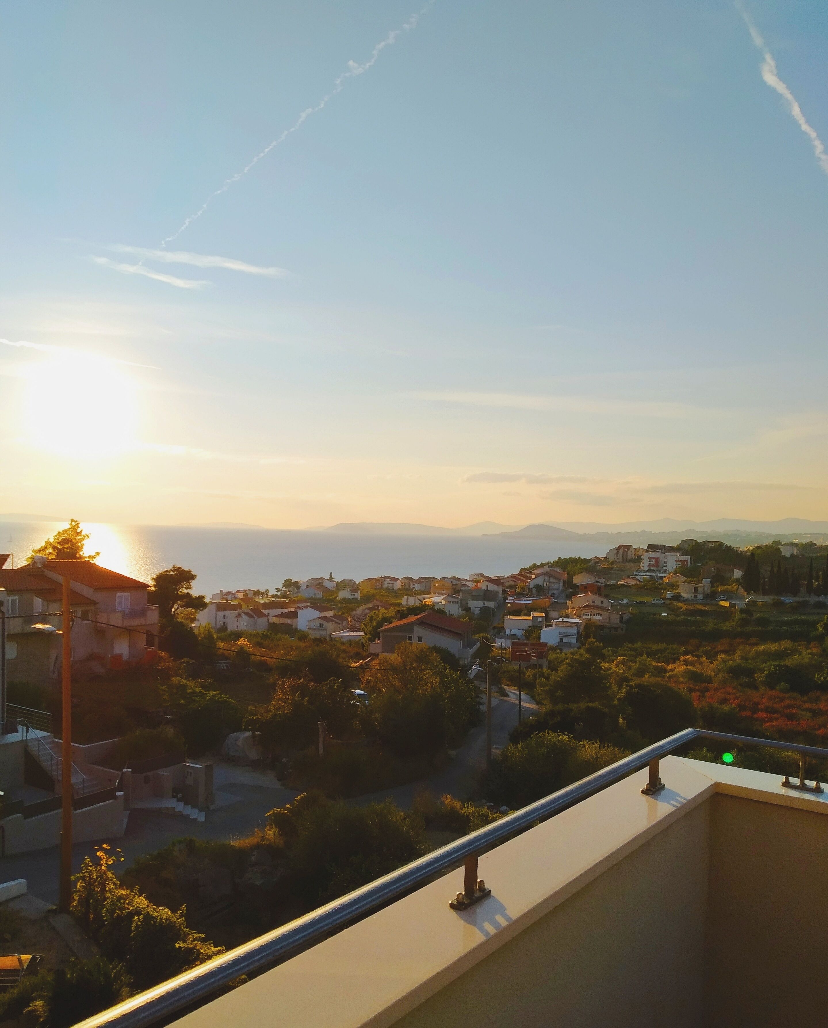 A balcony with a view of a residential area during sunset.