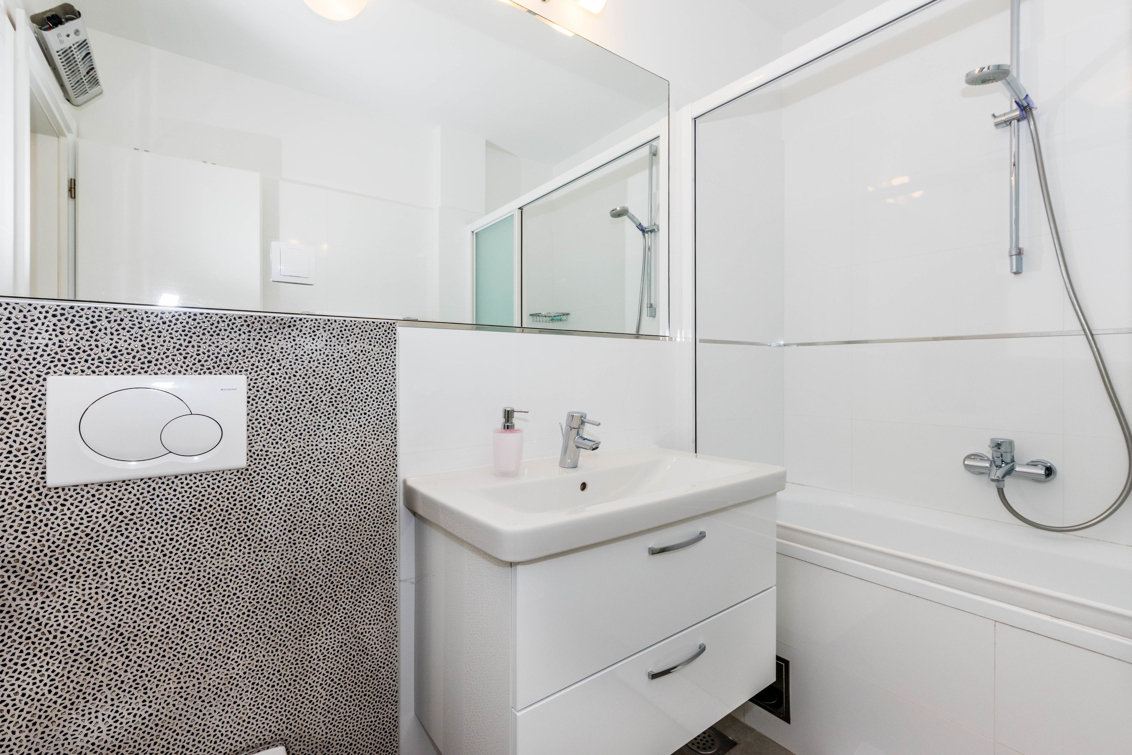 Une salle de bain avec un lavabo blanc, un miroir et une douche.