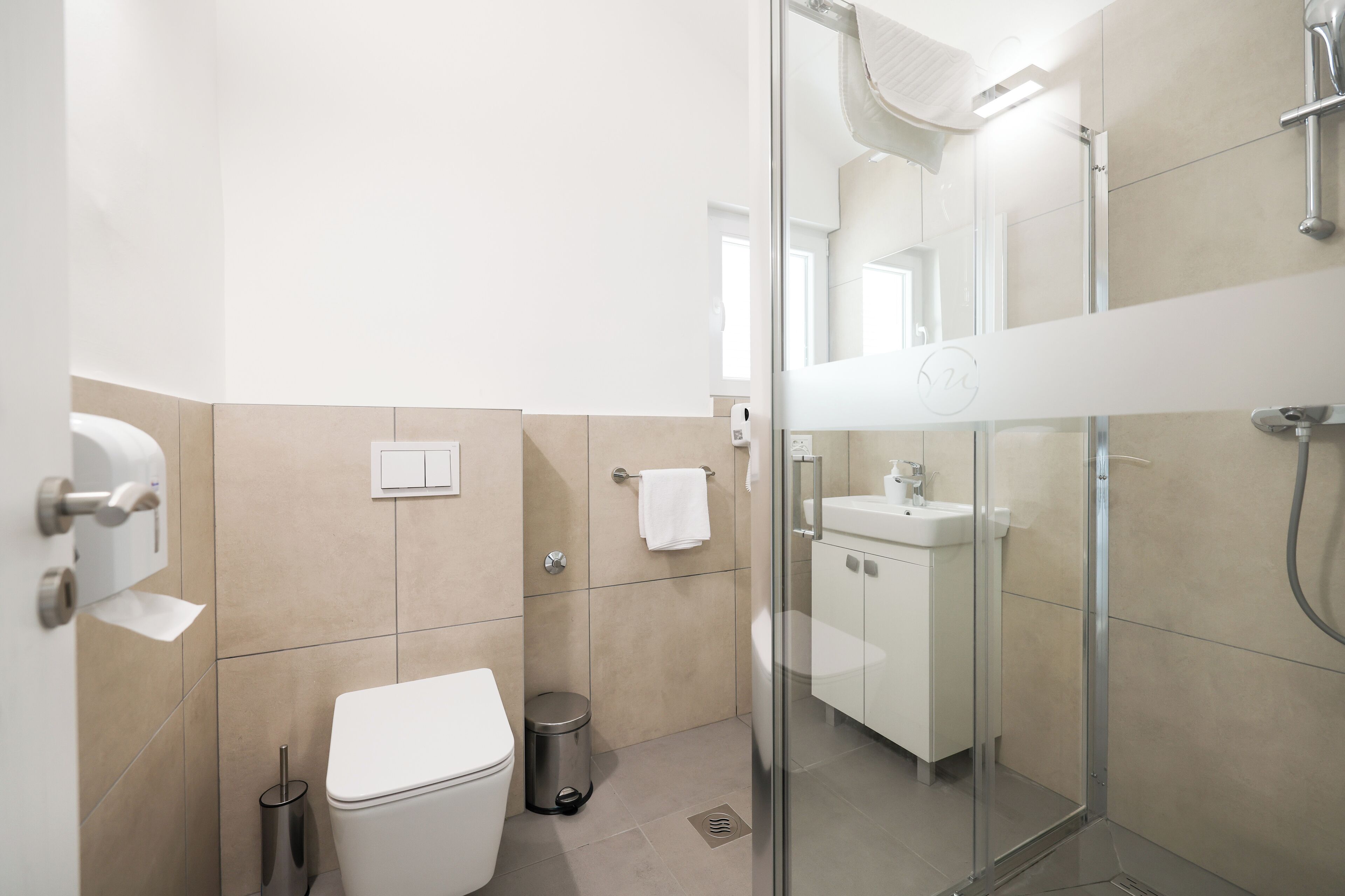 A modern bathroom with a toilet, bidet, and glass-enclosed shower.
