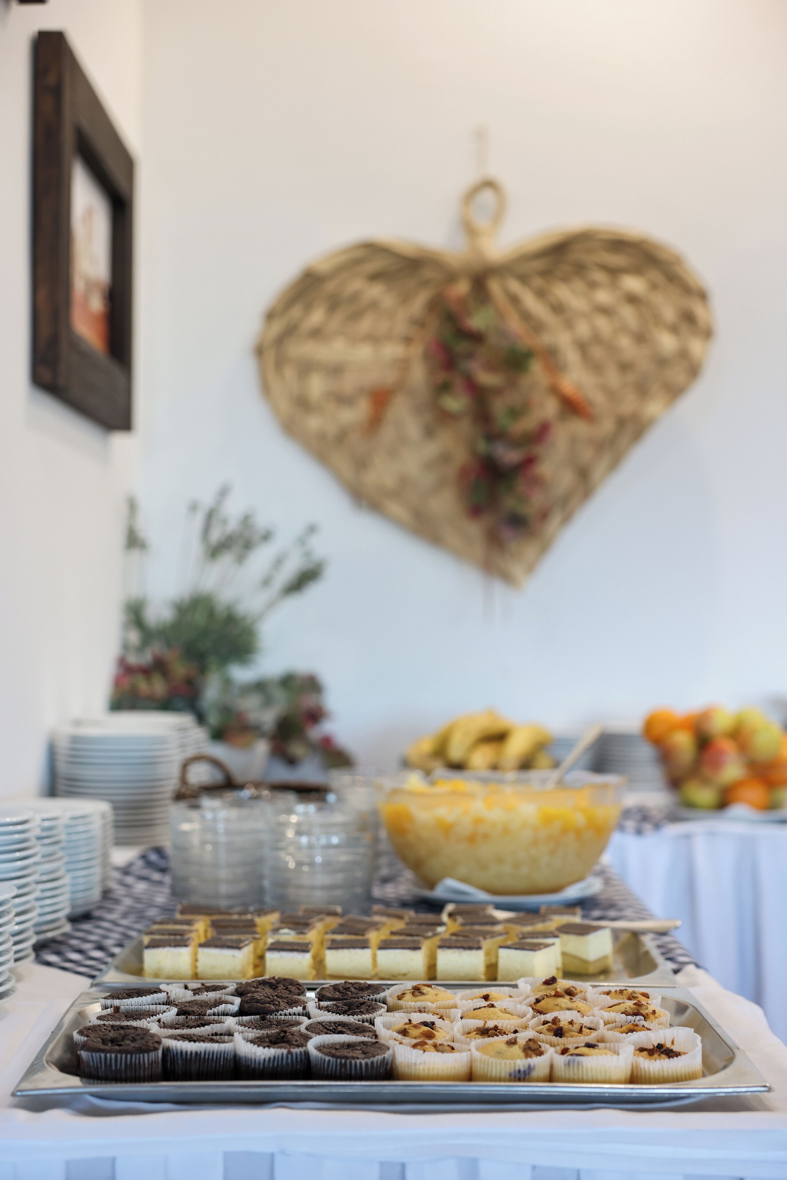 A buffet table with various desserts and a decorative heart-shaped wall hanging.