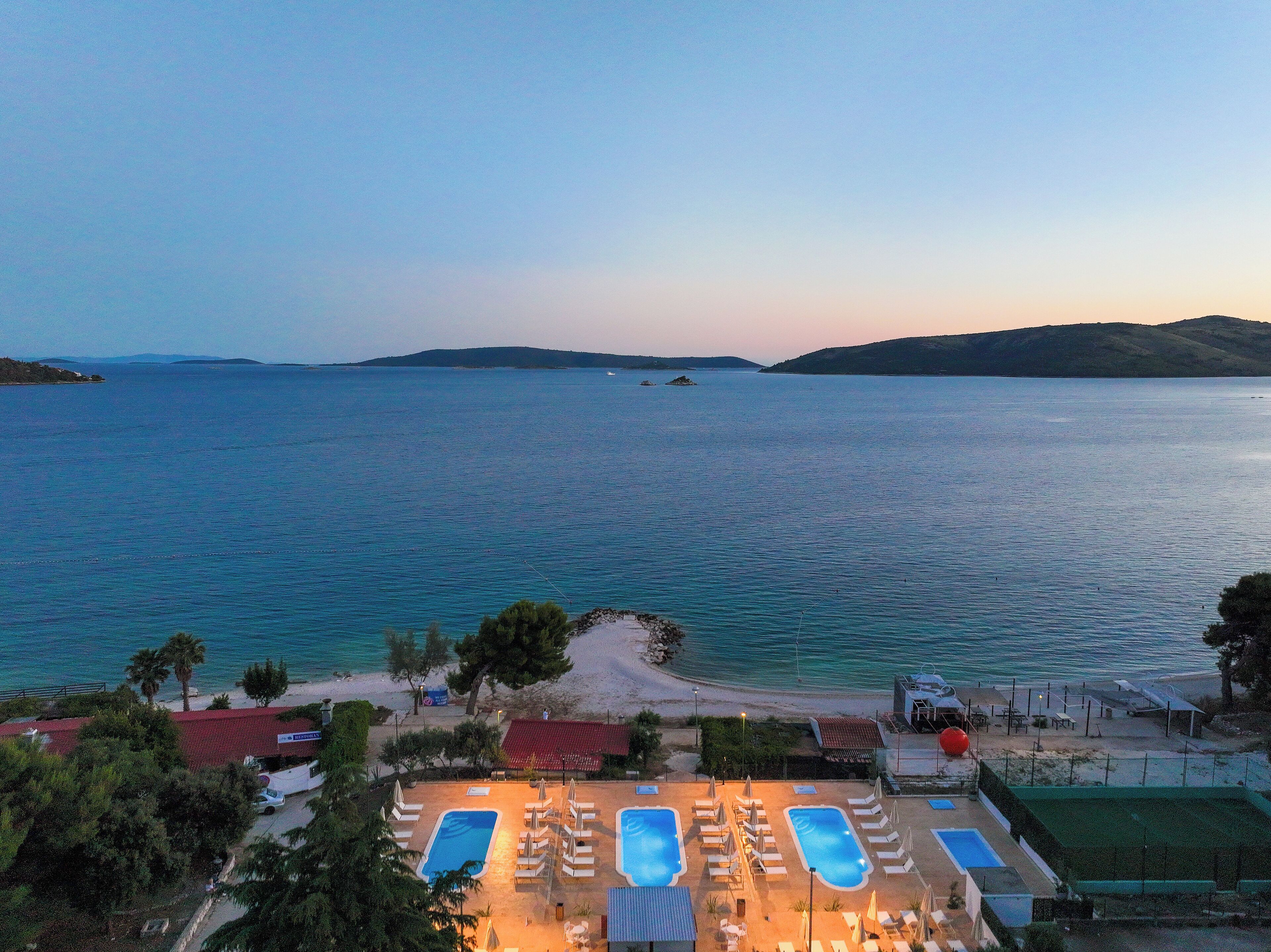 A resort with multiple swimming pools, a beach area, and a view of the sea.